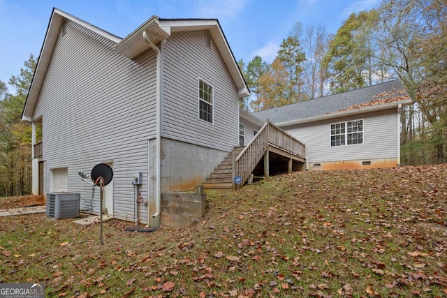 rear view of property with central air condition unit, stairs, and crawl space