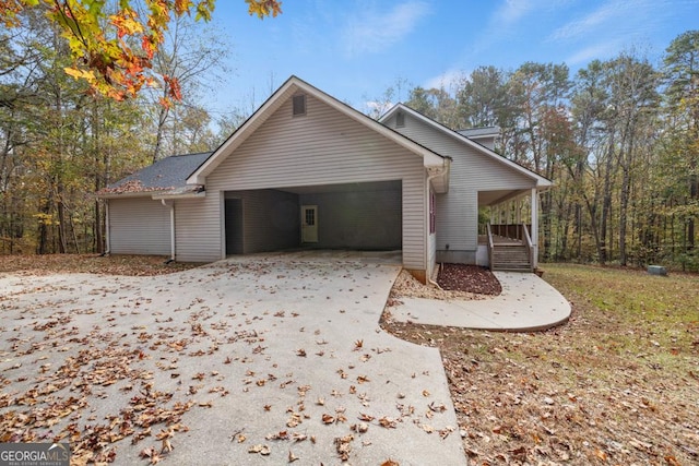 view of side of property featuring concrete driveway, a porch, and an attached garage