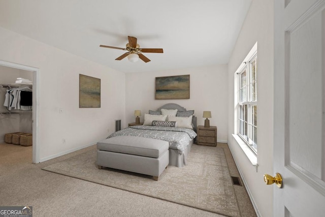 bedroom with ceiling fan, carpet flooring, visible vents, baseboards, and a walk in closet