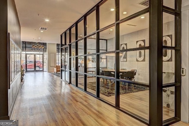 interior space with expansive windows, visible vents, wood finished floors, and french doors