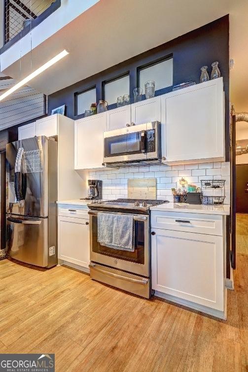 kitchen with light wood-type flooring, white cabinetry, appliances with stainless steel finishes, and light countertops