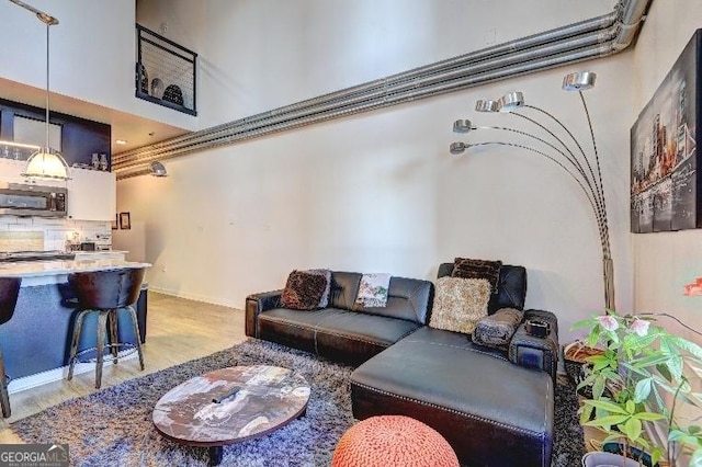 living room featuring light wood-style floors and a towering ceiling