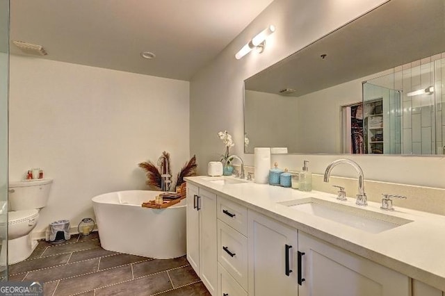 bathroom with a soaking tub, toilet, double vanity, and a sink