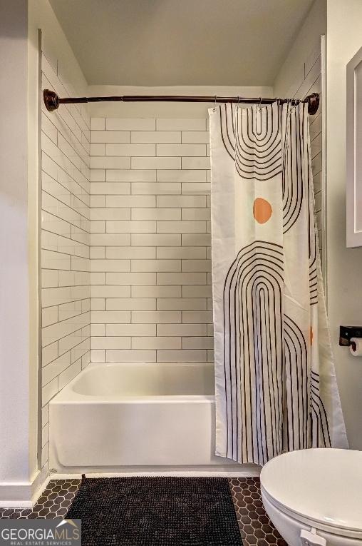 bathroom featuring tile patterned flooring, toilet, and shower / tub combo