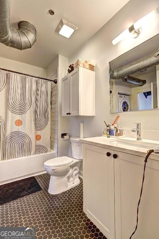 full bath with toilet, washer / dryer, shower / tub combo with curtain, and vanity