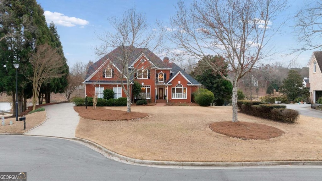 view of front of home with a chimney and curved driveway