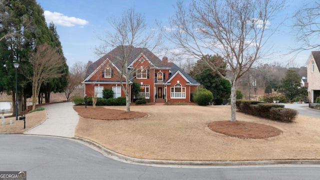 view of front of home with a chimney and curved driveway