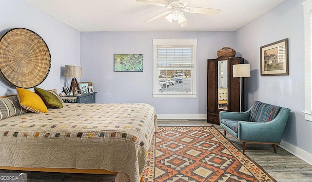bedroom with a ceiling fan, baseboards, and wood finished floors