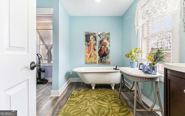 full bathroom with a freestanding bath, baseboards, and wood finished floors