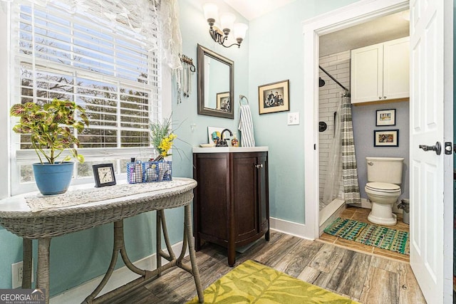 full bath featuring toilet, a stall shower, vanity, wood finished floors, and baseboards