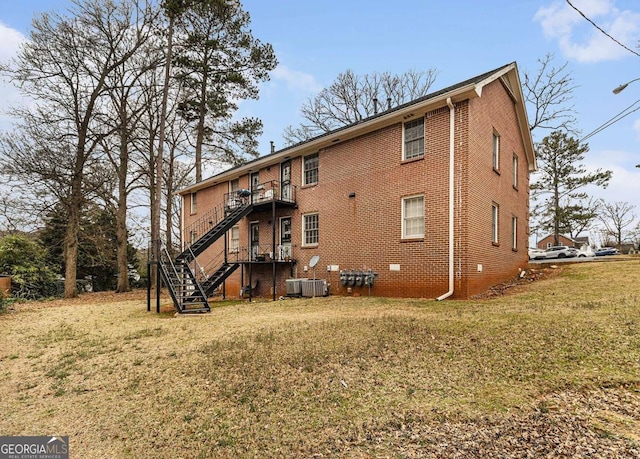 rear view of property featuring central air condition unit, brick siding, stairs, crawl space, and a lawn