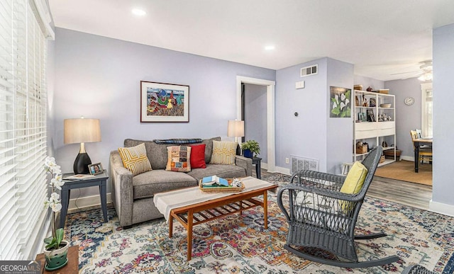 living room with visible vents, ceiling fan, and baseboards