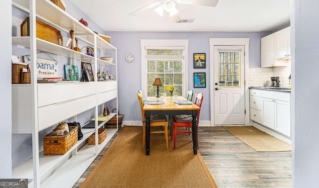 dining space with a ceiling fan, baseboards, visible vents, and wood finished floors