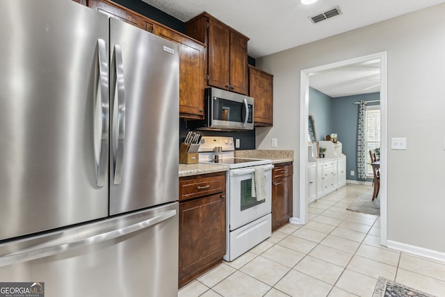 kitchen featuring stainless steel appliances, light countertops, visible vents, light tile patterned flooring, and baseboards