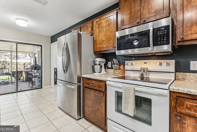 kitchen featuring a textured ceiling, stainless steel appliances, light tile patterned flooring, and visible vents