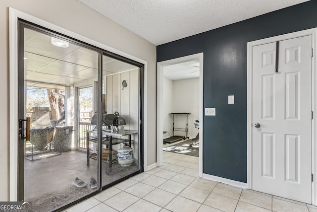 interior space with light tile patterned floors, a textured ceiling, and baseboards