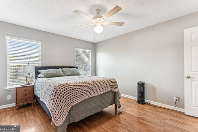 bedroom with light wood-style floors, a ceiling fan, baseboards, and a textured ceiling