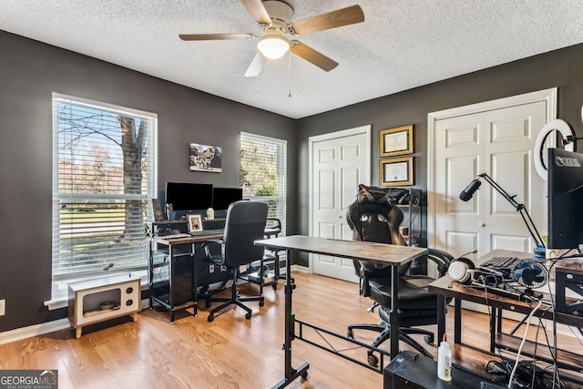 office space with a ceiling fan, a textured ceiling, baseboards, and wood finished floors