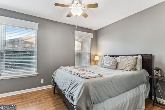 bedroom featuring ceiling fan, baseboards, and wood finished floors