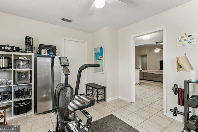 exercise area featuring visible vents, a ceiling fan, light tile patterned flooring, a textured ceiling, and baseboards