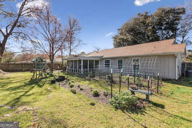 back of property with a vegetable garden, a sunroom, fence, a yard, and a playground