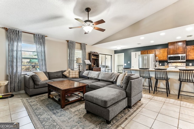 living room featuring lofted ceiling, recessed lighting, a ceiling fan, light tile patterned flooring, and a textured ceiling