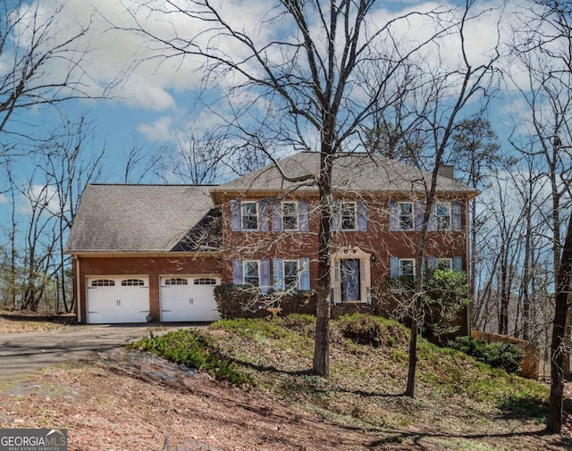 colonial house with a garage, driveway, and a chimney