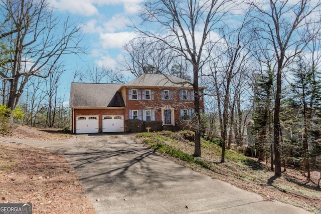 colonial inspired home featuring a garage, aphalt driveway, and brick siding