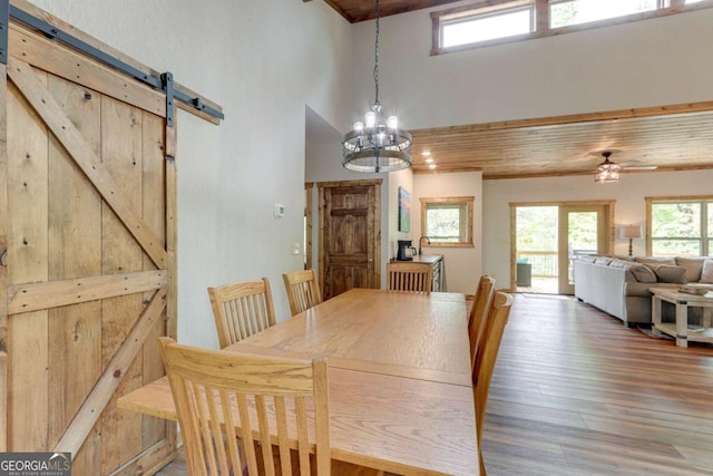 dining room with wood finished floors, a barn door, wooden ceiling, and a healthy amount of sunlight