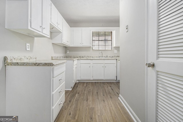 6437 Stone Way, Morrow, GA 30260 - kitchen with a sink, light countertops, white cabinetry, baseboards, and light wood-type flooring