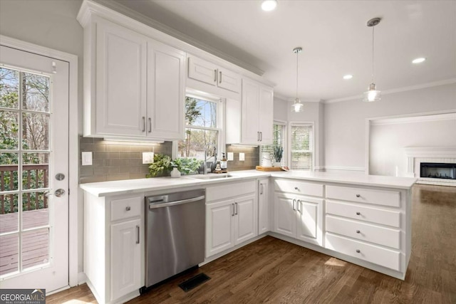 kitchen featuring light countertops, backsplash, dark wood-type flooring, a sink, and dishwasher