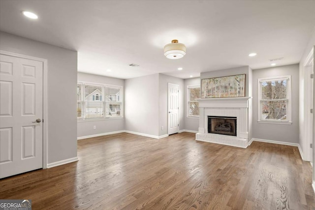 unfurnished living room featuring a fireplace, wood finished floors, and baseboards