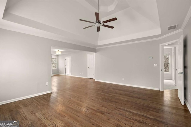 unfurnished living room featuring a ceiling fan, visible vents, baseboards, a tray ceiling, and dark wood finished floors