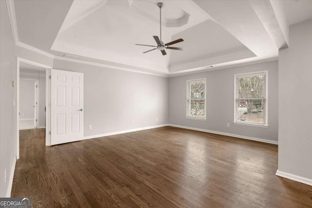 unfurnished room featuring a raised ceiling, dark wood finished floors, baseboards, and ceiling fan