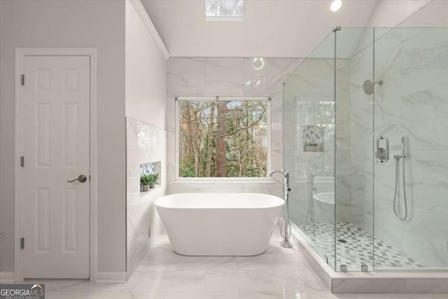 bathroom with a stall shower, marble finish floor, a soaking tub, and tile walls