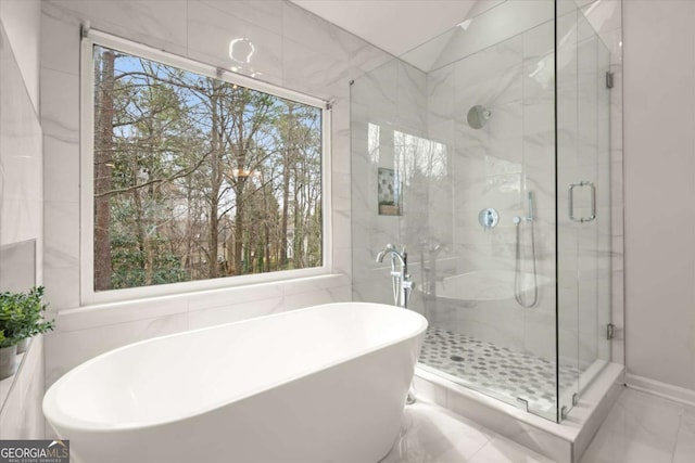 bathroom with vaulted ceiling, marble finish floor, a stall shower, and a soaking tub