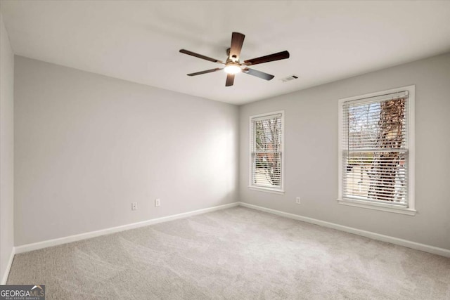 spare room with carpet floors, visible vents, baseboards, and a ceiling fan