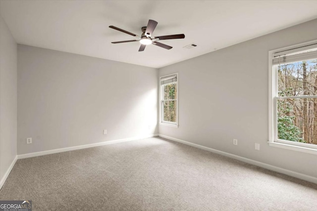 carpeted empty room with a healthy amount of sunlight, baseboards, and visible vents