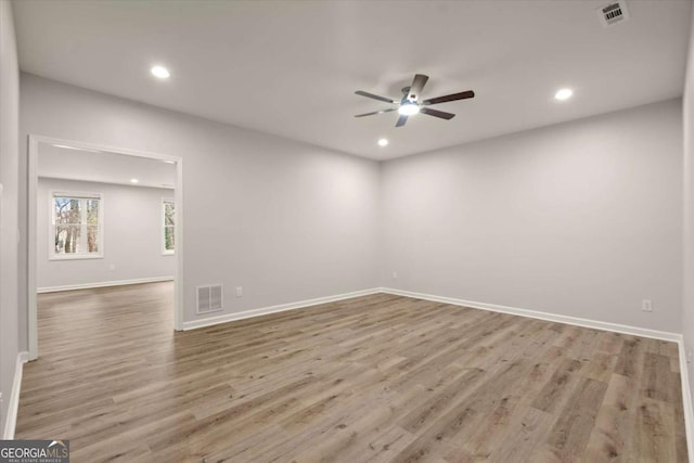 spare room with a ceiling fan, visible vents, and wood finished floors