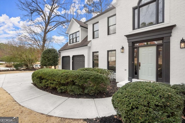 doorway to property with a garage and brick siding