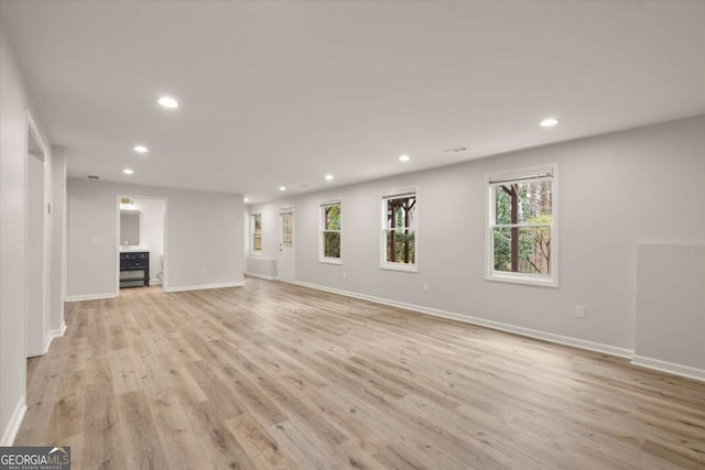 unfurnished living room with light wood-type flooring, baseboards, and recessed lighting