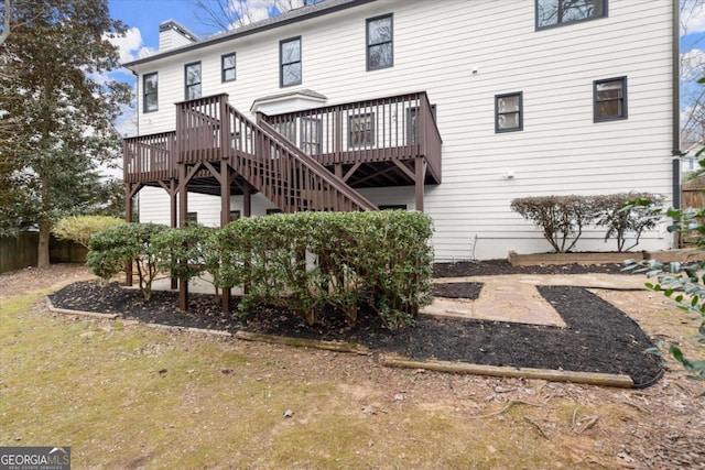 rear view of house with a chimney, fence, a deck, and stairs