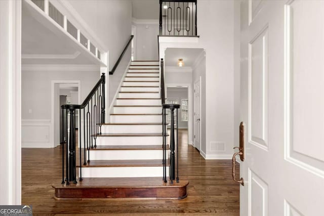 foyer entrance with dark wood-style floors, ornamental molding, stairway, and visible vents