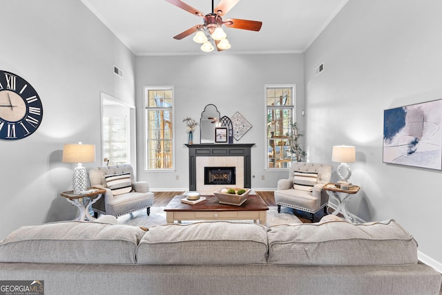 living room with a fireplace, visible vents, wood finished floors, and ornamental molding