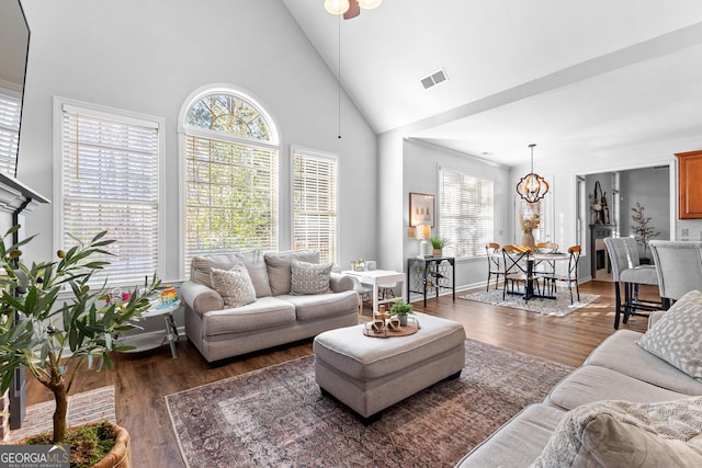 living area featuring a healthy amount of sunlight, high vaulted ceiling, visible vents, and wood finished floors