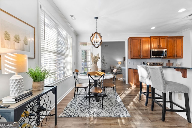 dining space with recessed lighting, dark wood-style flooring, visible vents, ornamental molding, and an inviting chandelier