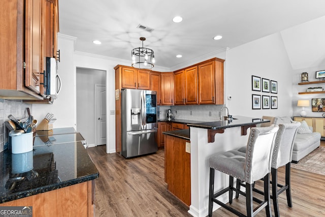 kitchen with a peninsula, brown cabinetry, stainless steel appliances, and wood finished floors