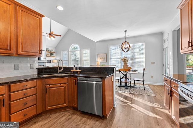 kitchen featuring stainless steel appliances, brown cabinets, a sink, and a peninsula