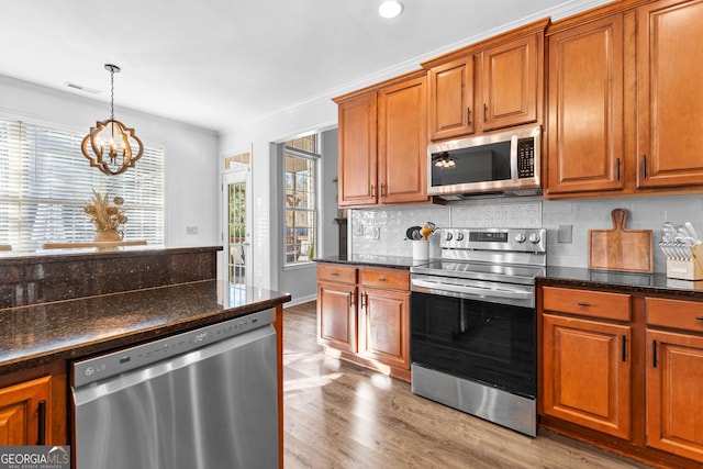 kitchen featuring stainless steel appliances, brown cabinetry, visible vents, and backsplash