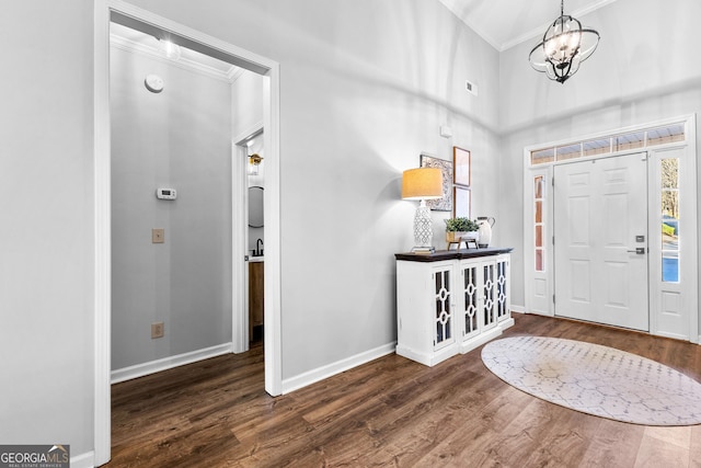 entryway with a chandelier, baseboards, dark wood finished floors, and crown molding